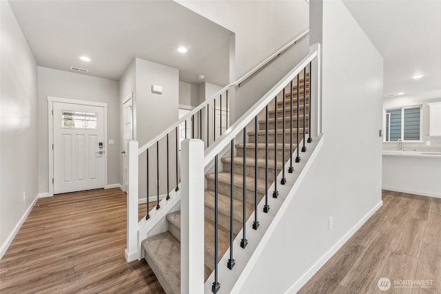 foyer entrance with baseboards, recessed lighting, wood finished floors, and stairs