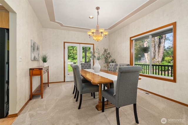 dining room featuring a chandelier, light carpet, baseboards, and french doors