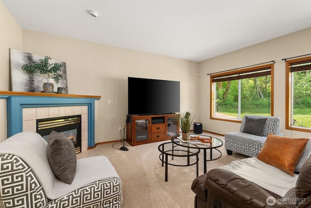 carpeted living room featuring baseboards and a tiled fireplace