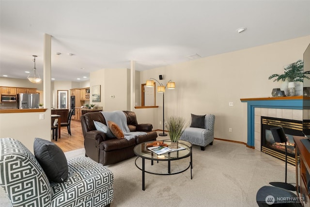 living room featuring a tile fireplace, recessed lighting, and light colored carpet