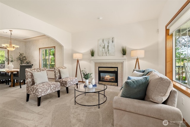 living room with a chandelier, healthy amount of natural light, carpet floors, and a fireplace