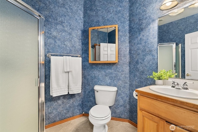 bathroom featuring a stall shower, toilet, vanity, baseboards, and wallpapered walls