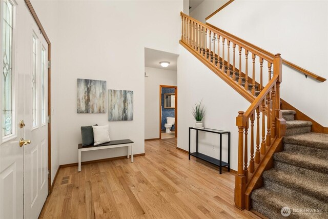 entrance foyer with light wood-style floors, stairs, and baseboards
