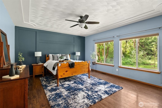 bedroom featuring wood finished floors, baseboards, and a ceiling fan