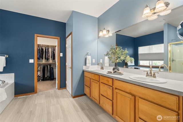 full bath with double vanity, a stall shower, a bath, a spacious closet, and baseboards