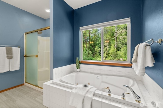 bathroom with a stall shower, a jetted tub, and baseboards