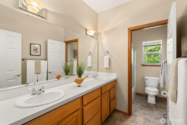 full bathroom with toilet, double vanity, and baseboards