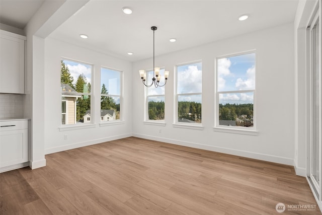 unfurnished dining area with an inviting chandelier, recessed lighting, baseboards, and light wood-style floors