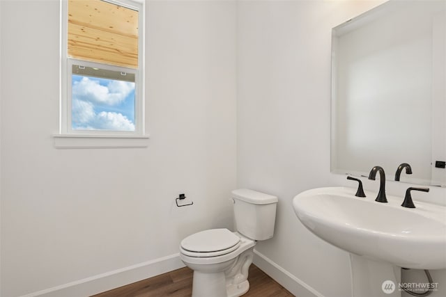 half bath with a sink, baseboards, toilet, and wood finished floors