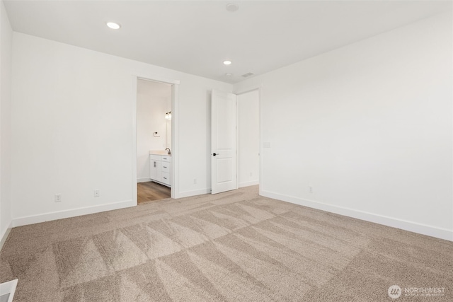 unfurnished bedroom with baseboards, recessed lighting, ensuite bath, and light colored carpet