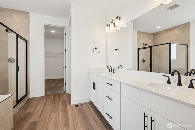 full bathroom with a sink, a stall shower, and wood finished floors
