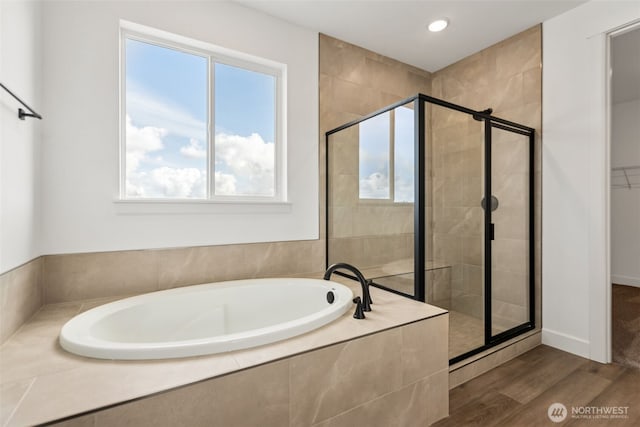 bathroom featuring a shower stall, a healthy amount of sunlight, a bath, and wood finished floors
