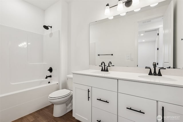bathroom featuring double vanity, a sink, wood finished floors, and toilet