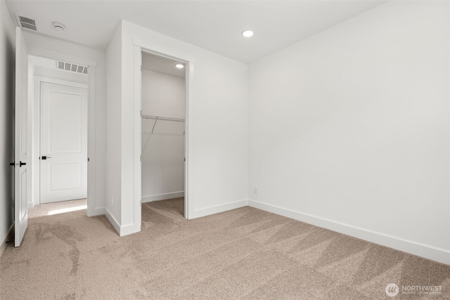 unfurnished bedroom featuring carpet floors, baseboards, a walk in closet, and visible vents