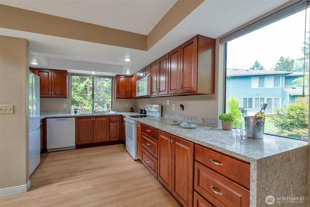 25432 213th Pl SE Unit 4, Maple Valley, WA 98038 - kitchen featuring white appliances, light wood-style floors, brown cabinets, light stone counters, and a sink