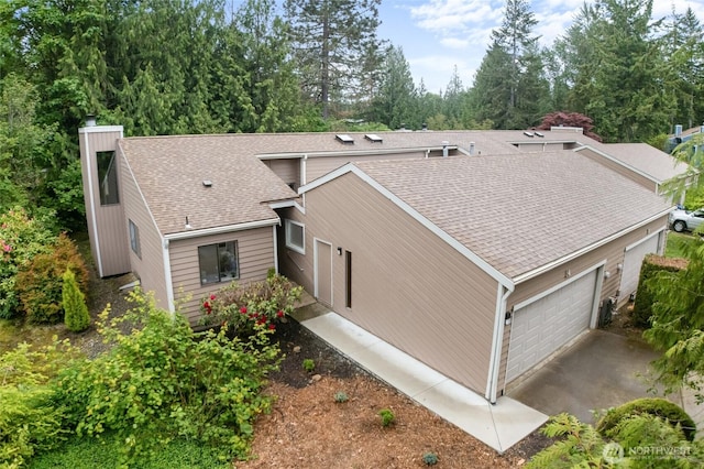 25432 213th Pl SE Unit 4, Maple Valley, WA 98038 - view of side of home with an attached garage, a shingled roof, a chimney, view of scattered trees, and driveway