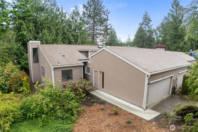 25432 213th Pl SE Unit 4, Maple Valley, WA 98038 - view of home's exterior with a chimney, an attached garage, roof with shingles, asphalt driveway, and view of wooded area