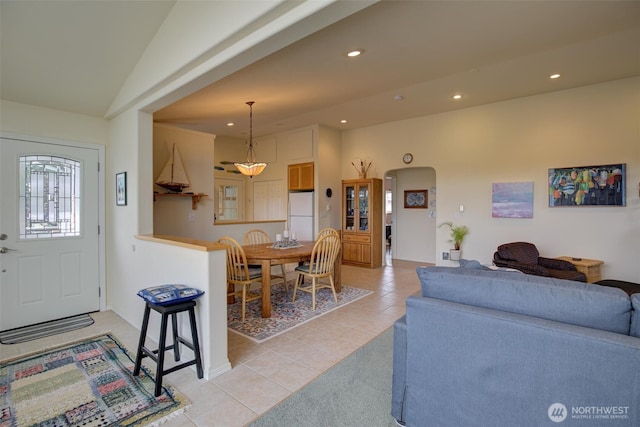 living room with arched walkways, vaulted ceiling, light tile patterned floors, baseboards, and recessed lighting