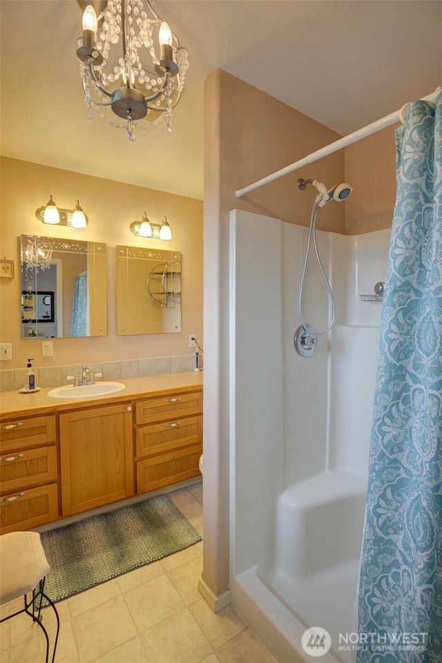 full bath with tile patterned flooring, a shower with shower curtain, a chandelier, and vanity