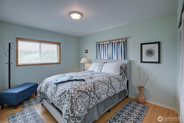bedroom featuring baseboards, wood finished floors, and a closet