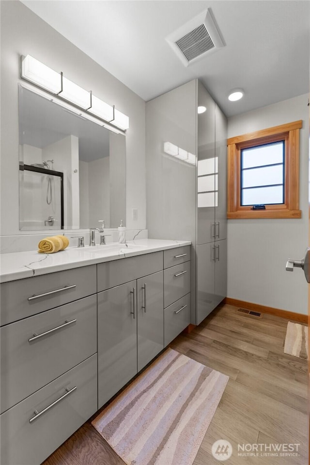 full bathroom featuring wood finished floors, visible vents, baseboards, and vanity