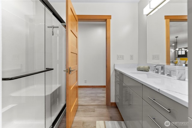 full bathroom with a stall shower, baseboards, vanity, and wood finished floors