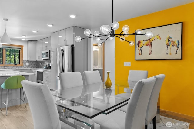 dining area featuring baseboards, recessed lighting, a notable chandelier, and light wood-type flooring