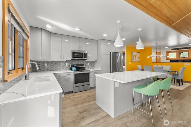 kitchen with a sink, light wood finished floors, stainless steel appliances, and a center island