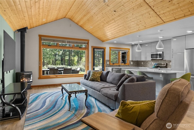 living area featuring a wood stove, light wood-type flooring, and vaulted ceiling
