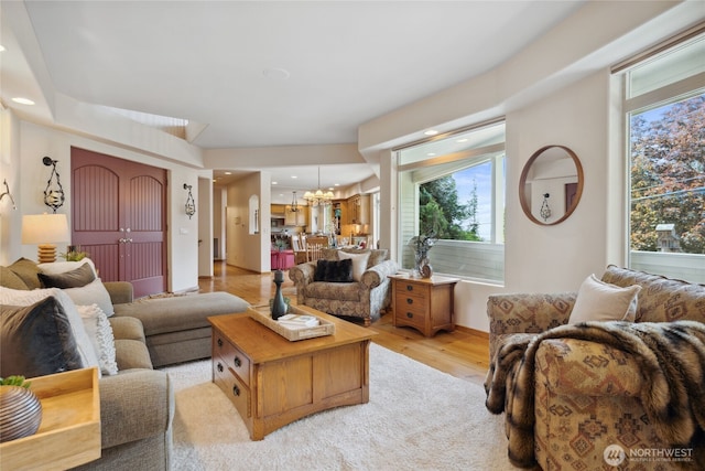living area with a chandelier, healthy amount of natural light, light wood-type flooring, and recessed lighting