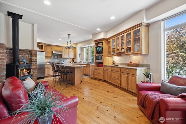 living area with healthy amount of natural light, recessed lighting, a wood stove, and light wood-style flooring