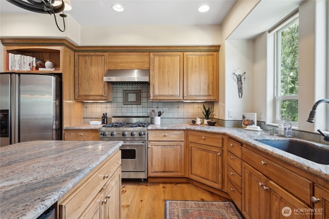 kitchen with appliances with stainless steel finishes, wall chimney range hood, a sink, healthy amount of natural light, and recessed lighting