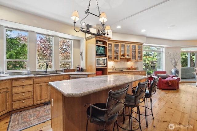 kitchen featuring a sink, stainless steel microwave, a center island, recessed lighting, and brown cabinetry