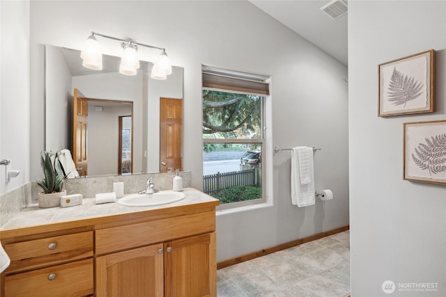 bathroom featuring lofted ceiling, vanity, and baseboards