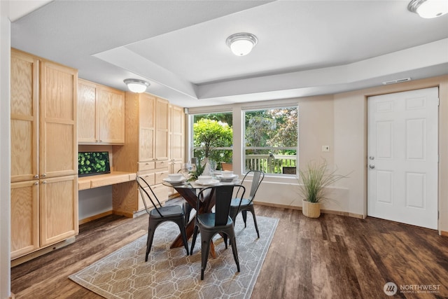 dining room with dark wood finished floors, baseboards, and a tray ceiling