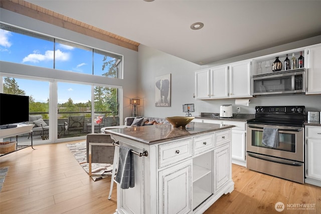 7806 Birch Bay Dr Unit 808, Blaine, WA 98230 - kitchen featuring appliances with stainless steel finishes, open shelves, white cabinetry, a kitchen island, and high vaulted ceiling