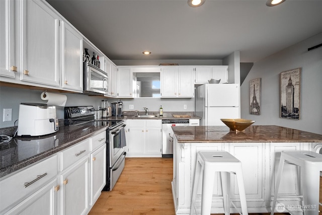 7806 Birch Bay Dr Unit 808, Blaine, WA 98230 - kitchen with appliances with stainless steel finishes, a sink, recessed lighting, white cabinetry, and a kitchen breakfast bar