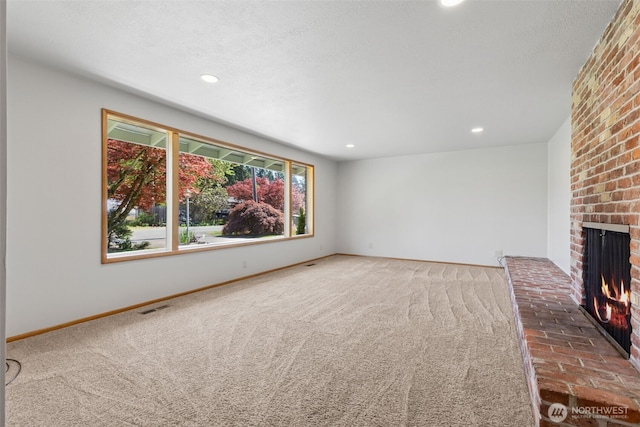 unfurnished living room with carpet flooring, a fireplace, recessed lighting, baseboards, and visible vents