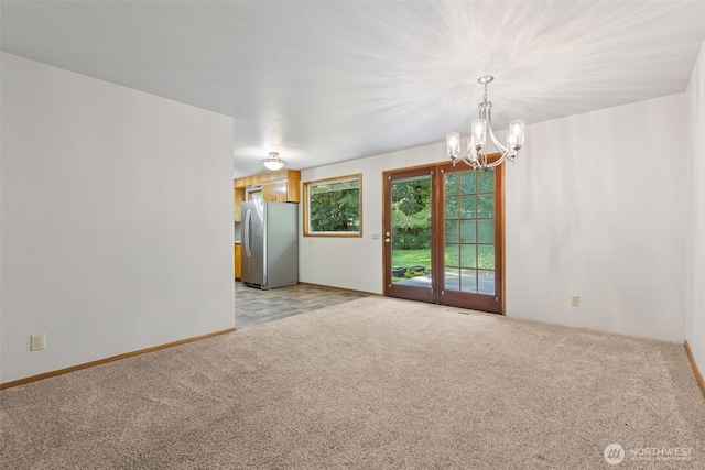 empty room with light colored carpet and a chandelier