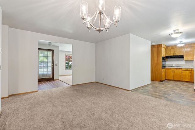 unfurnished living room featuring baseboards, light colored carpet, and an inviting chandelier