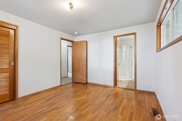 unfurnished bedroom featuring light wood-style floors, connected bathroom, baseboards, and visible vents