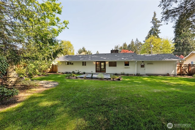 back of house with a lawn, a patio, fence, and a chimney