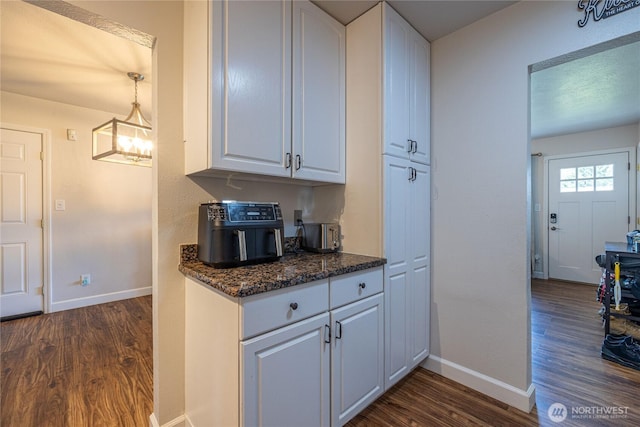 8803 Terrace Rd SW, Tacoma, WA 98498 - kitchen featuring dark wood finished floors, baseboards, white cabinetry, dark stone countertops, and a chandelier