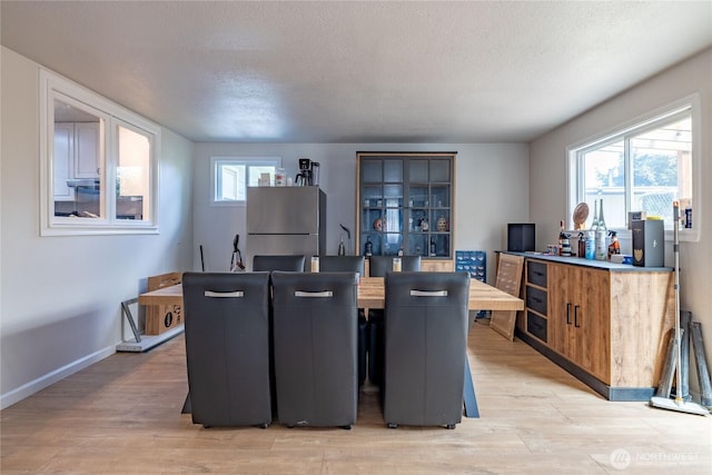 8803 Terrace Rd SW, Tacoma, WA 98498 - dining space featuring light wood-style floors, a textured ceiling, and baseboards