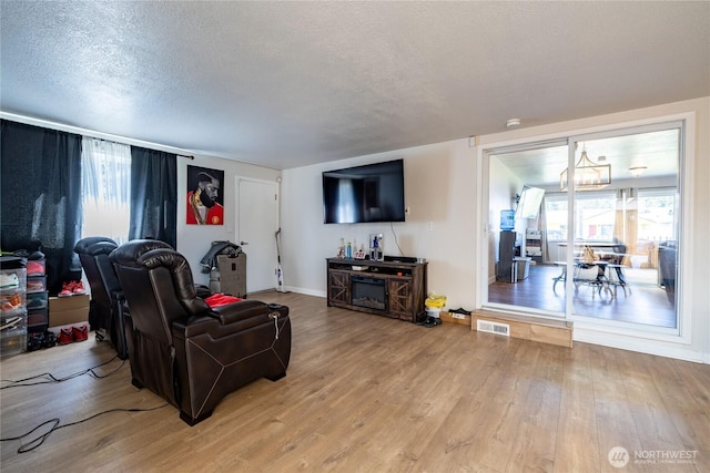 8803 Terrace Rd SW, Tacoma, WA 98498 - living room featuring light wood-style flooring, a textured ceiling, a chandelier, and baseboards