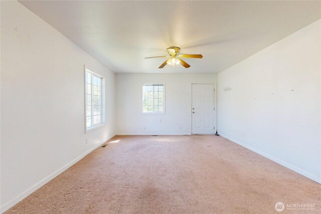 unfurnished room with a ceiling fan, light carpet, and baseboards