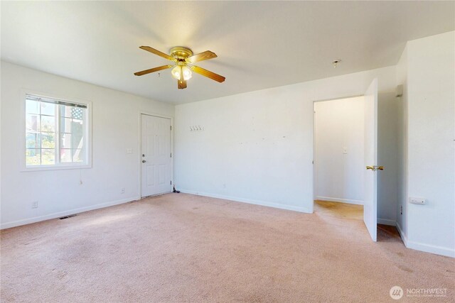 empty room featuring light carpet, a ceiling fan, and baseboards