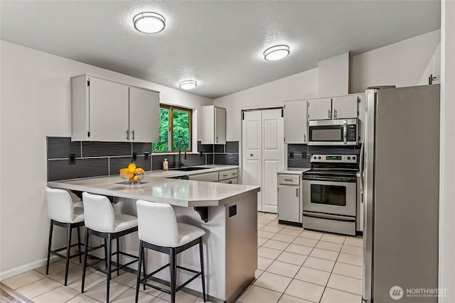 1027 Fishpond Rd, Kelso, WA 98626 - kitchen with stainless steel appliances, a peninsula, a sink, tasteful backsplash, and light countertops