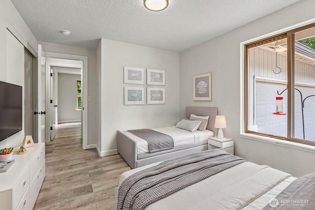 1027 Fishpond Rd, Kelso, WA 98626 - bedroom with light wood finished floors, multiple windows, baseboards, and a textured ceiling