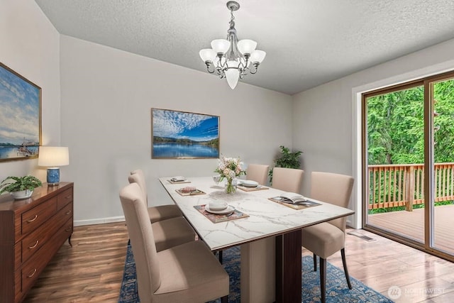1027 Fishpond Rd, Kelso, WA 98626 - dining room featuring a chandelier, wood finished floors, a textured ceiling, and baseboards